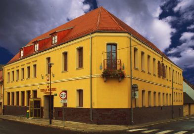 żółty budynek urzędu, pokryty czerwona cegłówką, widok od frontu
