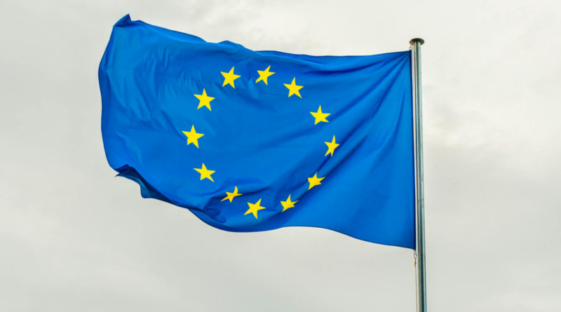 Flaga EU w niebieskim kolorze, a na niej gwiazdy ułożone w okrąg.