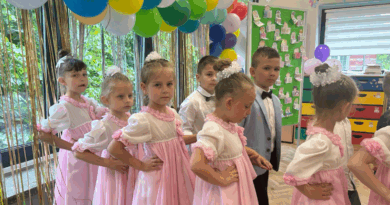 Siedmioro dzieci w różowych strojach, stoją w parach, przygotowują się do poloneza.