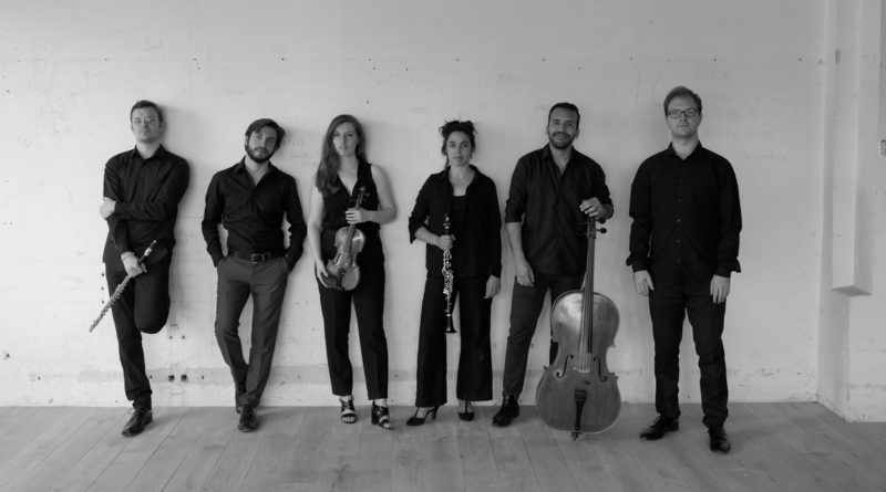 czarno-białe zdjęcie a na nim 6 młodych muzyków, stojących pod ścianą, jeden z mężczyzn z kontrabasem.