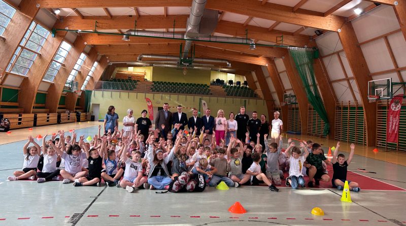 sala sportowa a w niej ponad 70. dzieci w wieku 7-9 lat ustawionych do zdjęcia grupowego.