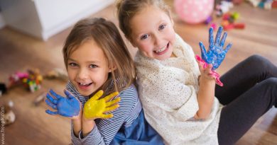 dwie dziewczynki pozujące do zdjęcia z pomalowanymi dłońmi.