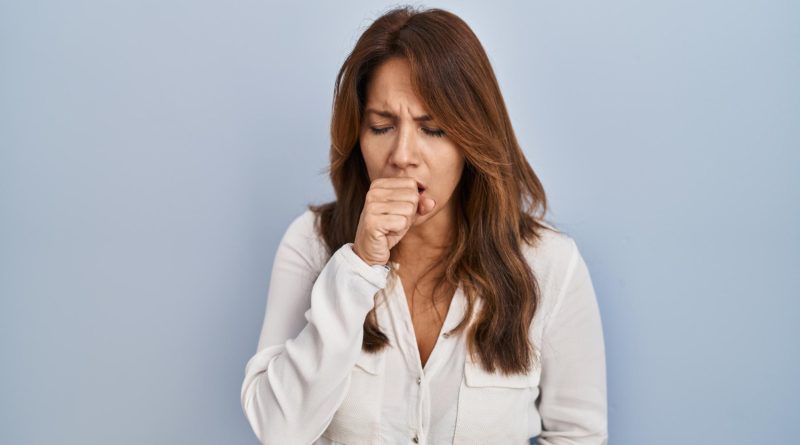 Kobieta, która kaszle na niebieskim tle.