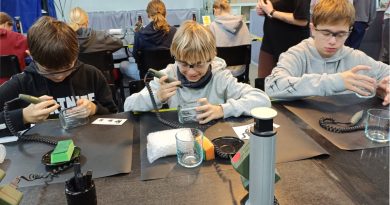 Trzech chłopców siedzących przy stołach rzemieślniczych, tworzących szklane gadżety.