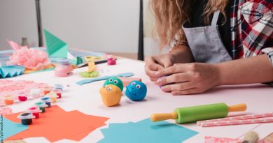 Dziecko siedzące przy stole i bawiące się plasteliną.