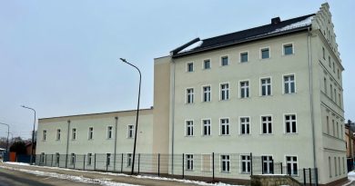 Trzykondygnacyjny budynek w kolorze szarości.