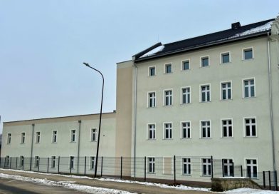 Trzykondygnacyjny budynek w kolorze szarości.