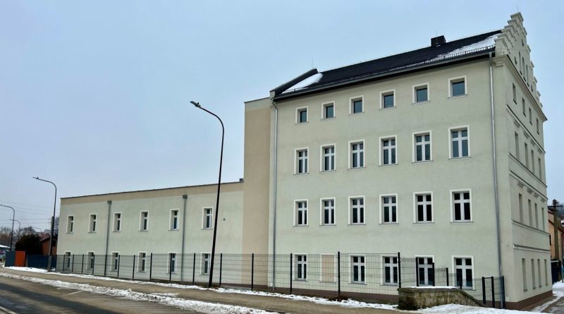 Trzykondygnacyjny budynek w kolorze szarości.