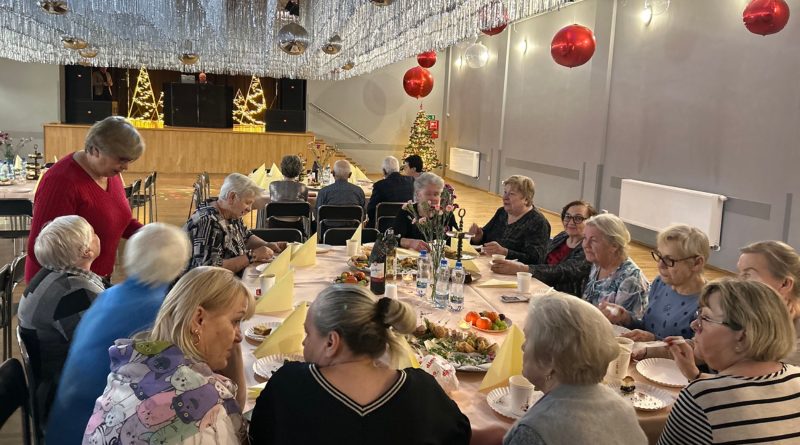 grupa mężczyzn i kobiet siedzących przy stolikach w udekorowanej sali widowiskowej.