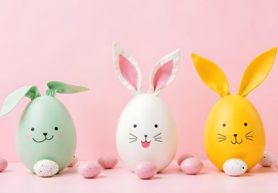 Różowe tło, a na nim zielone, białe oraz żółte jajka udekorowane jak wielkanocne zajączki.